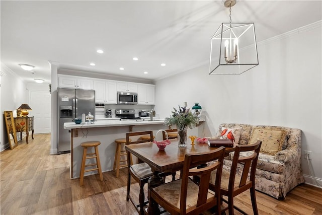 dining area with ornamental molding, sink, and light hardwood / wood-style flooring