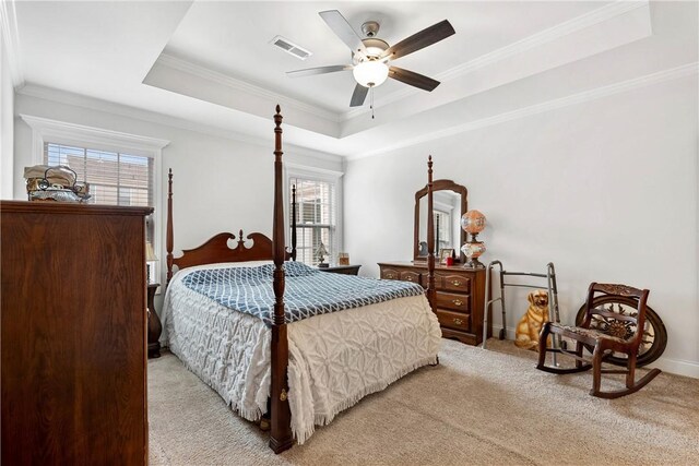 carpeted bedroom featuring a tray ceiling, ornamental molding, and ceiling fan