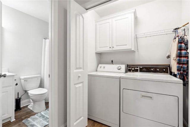 washroom featuring wood-type flooring, cabinets, and washing machine and clothes dryer