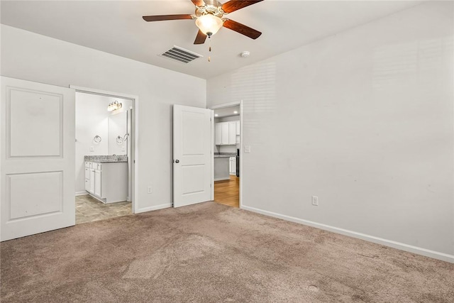 unfurnished bedroom featuring light carpet, ensuite bath, and ceiling fan