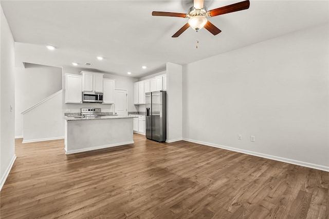 kitchen featuring light hardwood / wood-style flooring, ceiling fan, appliances with stainless steel finishes, white cabinetry, and a kitchen island