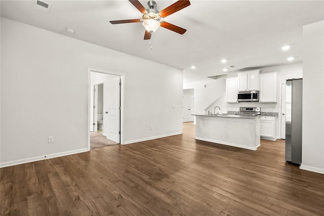 kitchen with sink, white cabinetry, stainless steel appliances, a barn door, and a kitchen island with sink