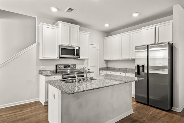 kitchen featuring appliances with stainless steel finishes, light stone countertops, a center island with sink, and white cabinets