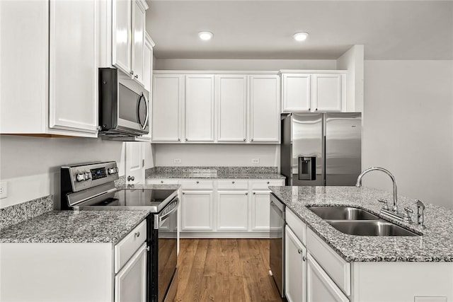 kitchen featuring sink, white cabinetry, stainless steel appliances, light stone counters, and light wood-type flooring