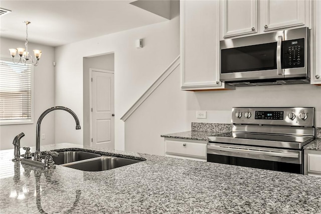 kitchen featuring sink, white cabinetry, hanging light fixtures, stone counters, and stainless steel appliances