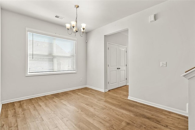 empty room featuring an inviting chandelier and light wood-type flooring