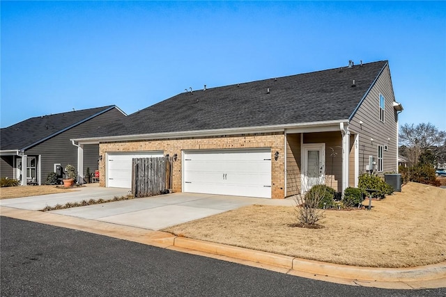 ranch-style home with a garage and central air condition unit