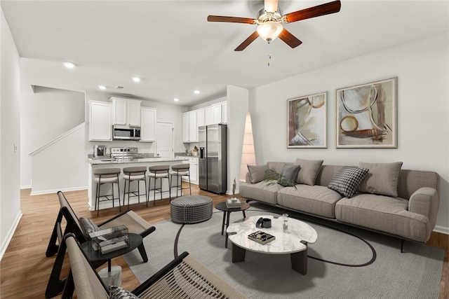 living room with light hardwood / wood-style flooring and ceiling fan