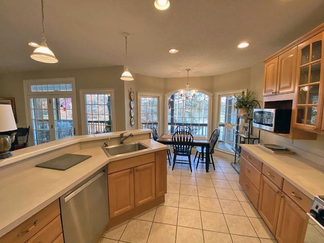 kitchen with sink, appliances with stainless steel finishes, hanging light fixtures, light tile patterned flooring, and a chandelier