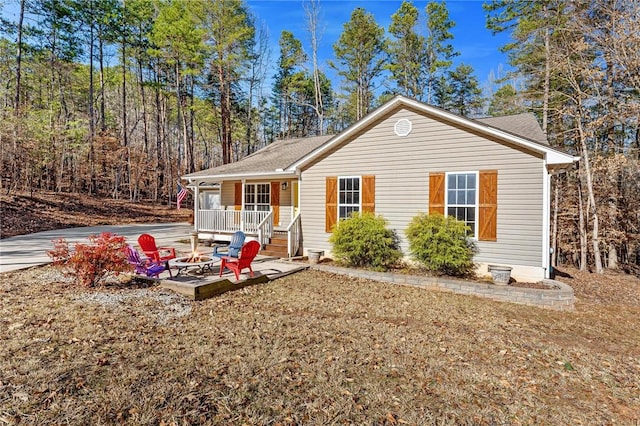 view of front facade with a porch, a front lawn, and an outdoor fire pit