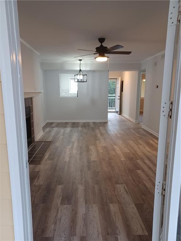 unfurnished living room featuring crown molding, a healthy amount of sunlight, dark hardwood / wood-style flooring, and a tiled fireplace