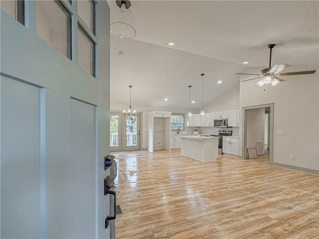 unfurnished living room featuring high vaulted ceiling, ceiling fan with notable chandelier, and light wood-type flooring