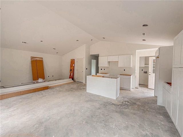 kitchen with lofted ceiling, a kitchen island, and white cabinets