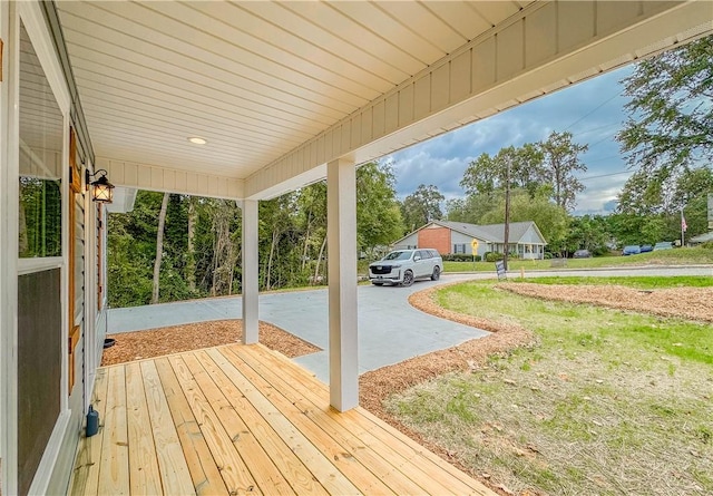 wooden deck featuring a porch and a lawn