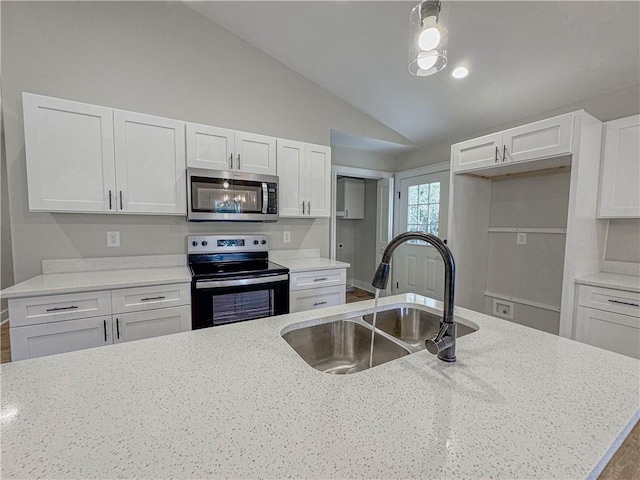 kitchen with sink, appliances with stainless steel finishes, white cabinetry, light stone countertops, and vaulted ceiling