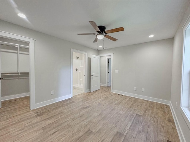 unfurnished bedroom with ensuite bath, light hardwood / wood-style flooring, ceiling fan, a walk in closet, and a closet