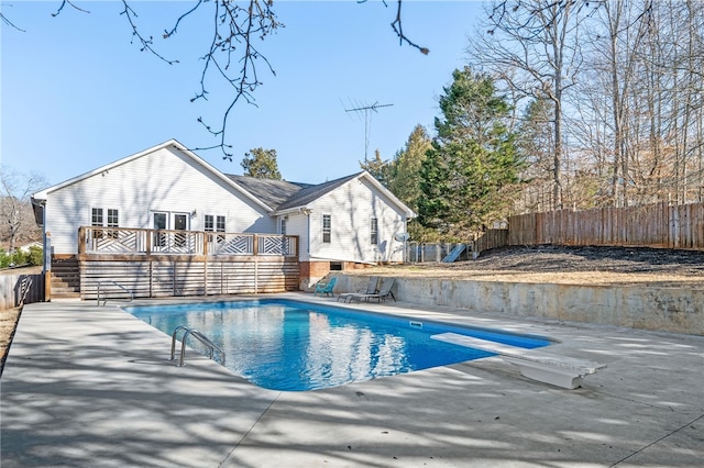 view of pool with a fenced in pool, a patio area, fence, a deck, and a diving board