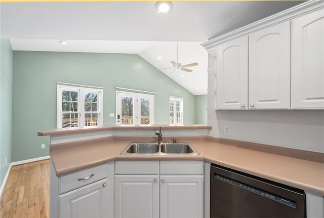 kitchen with dishwasher, vaulted ceiling, a sink, and white cabinets