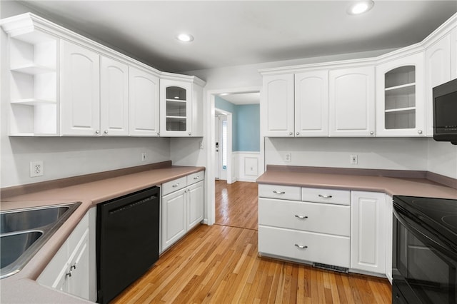 kitchen with white cabinets, a sink, light wood-style flooring, and black appliances