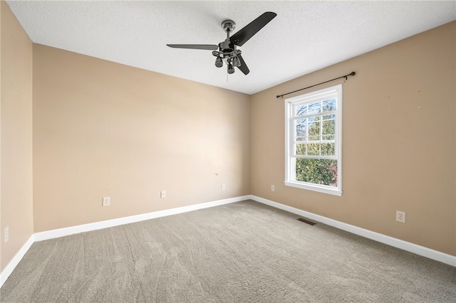 carpeted spare room featuring visible vents, ceiling fan, a textured ceiling, and baseboards