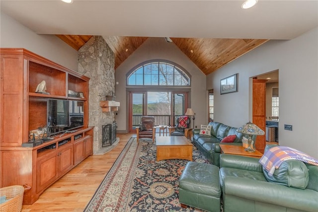 living room featuring high vaulted ceiling, wooden ceiling, a fireplace, and light hardwood / wood-style flooring