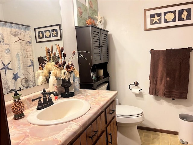 bathroom with toilet, vanity, and baseboards