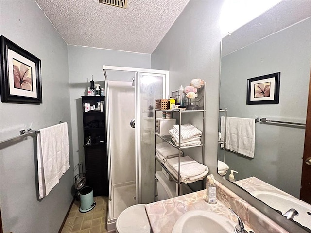 full bath featuring vanity, a textured ceiling, visible vents, and a shower stall