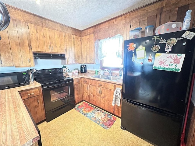 kitchen featuring tile patterned floors, light countertops, a sink, under cabinet range hood, and black appliances