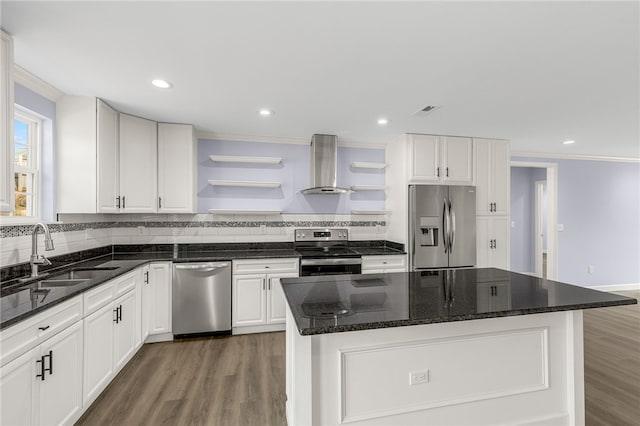 kitchen featuring sink, a center island, wall chimney range hood, stainless steel appliances, and white cabinets