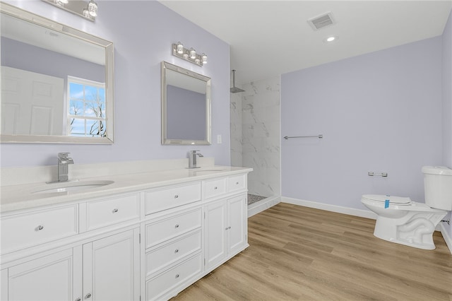 bathroom featuring tiled shower, vanity, toilet, and hardwood / wood-style floors