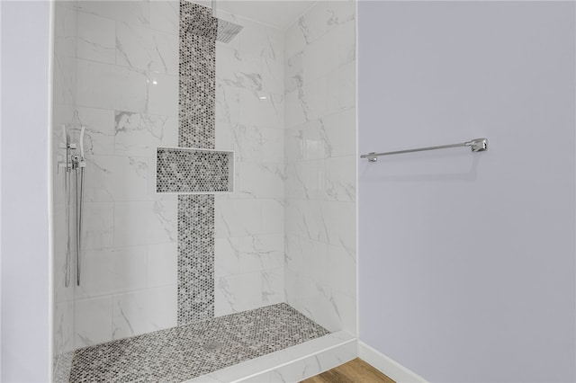 bathroom with hardwood / wood-style flooring and tiled shower