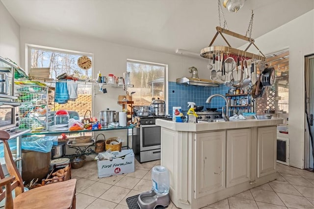 kitchen with white cabinetry, stainless steel range with gas stovetop, backsplash, and light tile patterned floors