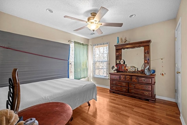 bedroom with ceiling fan, a textured ceiling, and light hardwood / wood-style floors