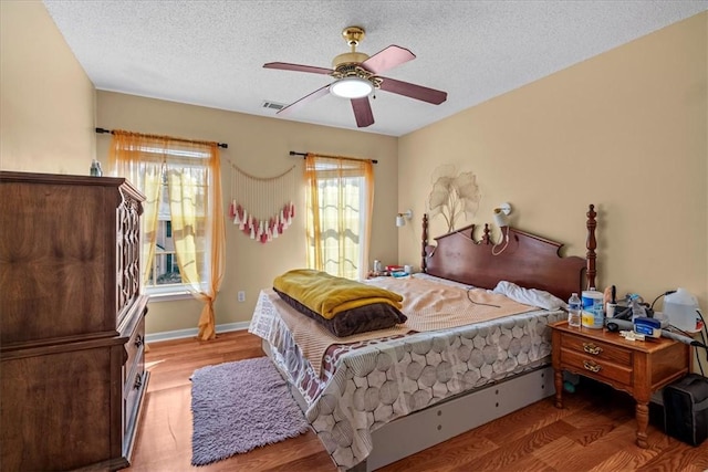 bedroom with hardwood / wood-style floors, a textured ceiling, and ceiling fan