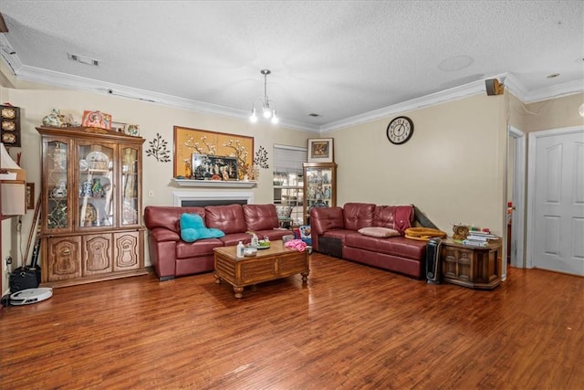 living room with wood-type flooring, ornamental molding, a notable chandelier, and a textured ceiling