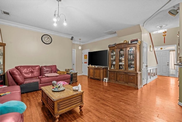 living room featuring ornamental molding, hardwood / wood-style floors, a textured ceiling, and a notable chandelier