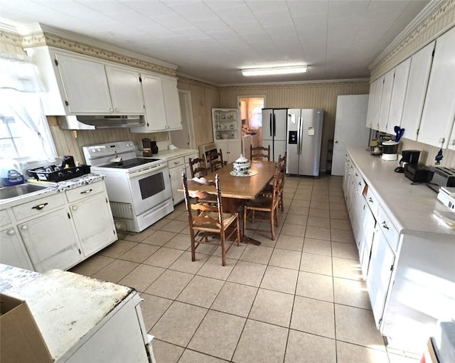 kitchen with electric stove, stainless steel fridge, and white cabinets