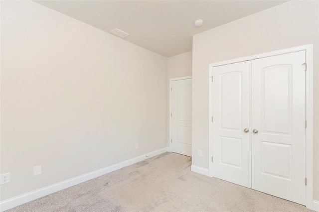 unfurnished bedroom featuring light carpet and a closet