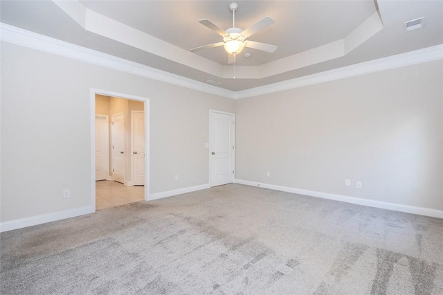 empty room with ceiling fan, ornamental molding, a raised ceiling, and light carpet