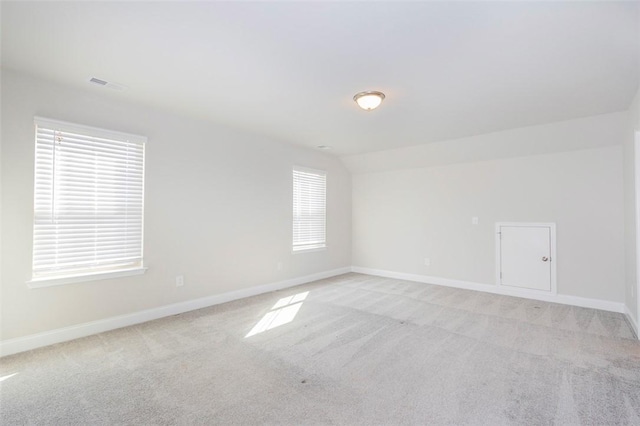 carpeted spare room with vaulted ceiling