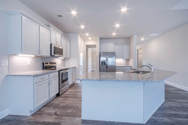 kitchen with sink, dark wood-type flooring, white cabinetry, a kitchen island with sink, and stainless steel appliances