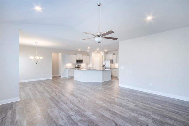 unfurnished living room featuring lofted ceiling, sink, ceiling fan with notable chandelier, and light wood-type flooring