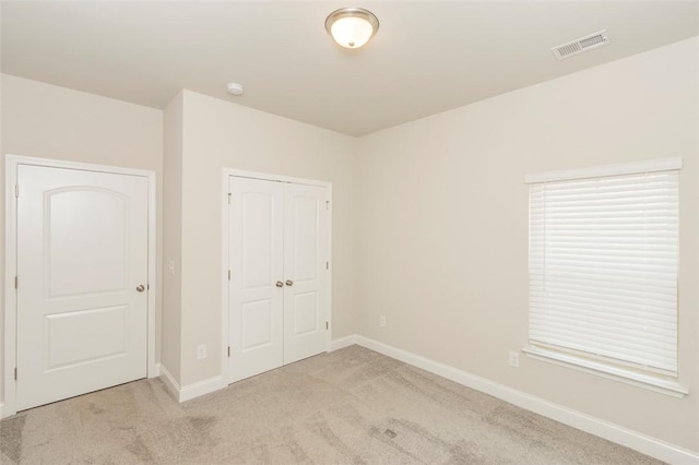 unfurnished bedroom with light colored carpet and a closet