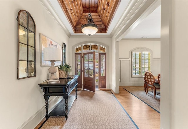 foyer entrance with a tray ceiling, wood ceiling, crown molding, and hardwood / wood-style flooring