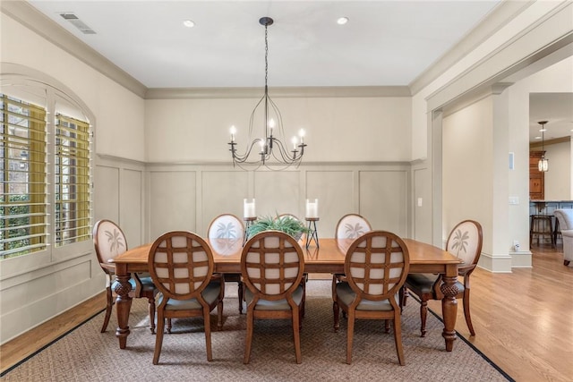 dining space with an inviting chandelier, crown molding, and hardwood / wood-style floors