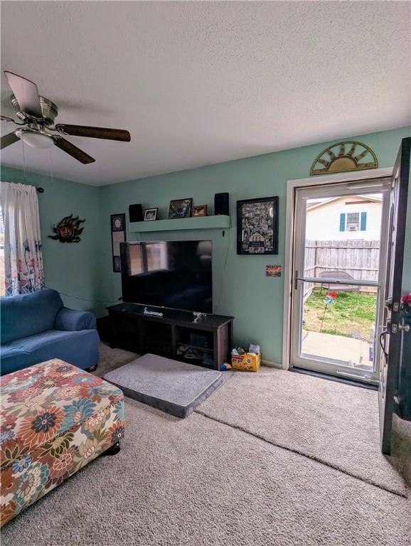 carpeted living room featuring ceiling fan and a textured ceiling