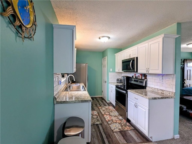 kitchen with tasteful backsplash, appliances with stainless steel finishes, sink, and white cabinets