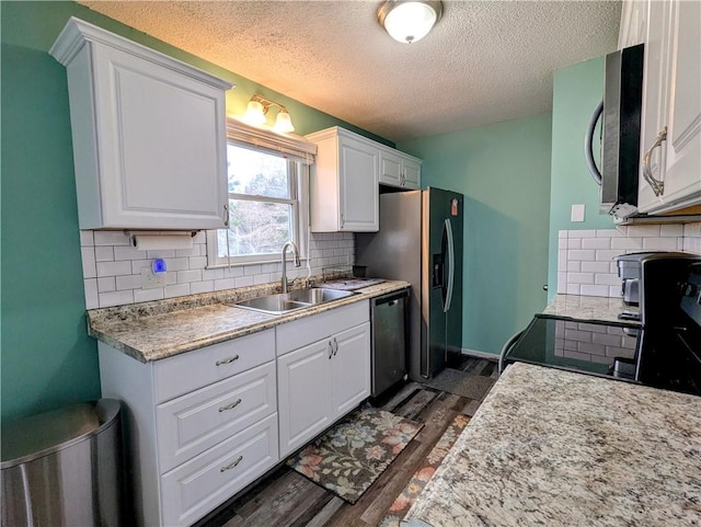 kitchen featuring dark wood-type flooring, sink, white cabinetry, appliances with stainless steel finishes, and backsplash