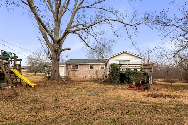 back of house featuring a wooden deck and a playground