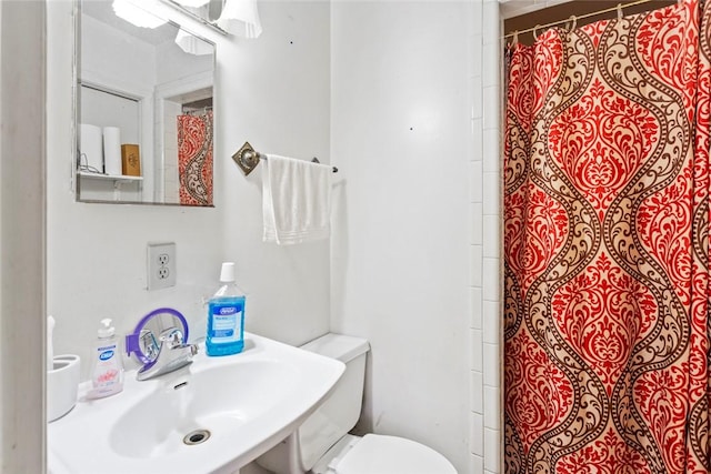 bathroom featuring sink, a shower with shower curtain, and toilet